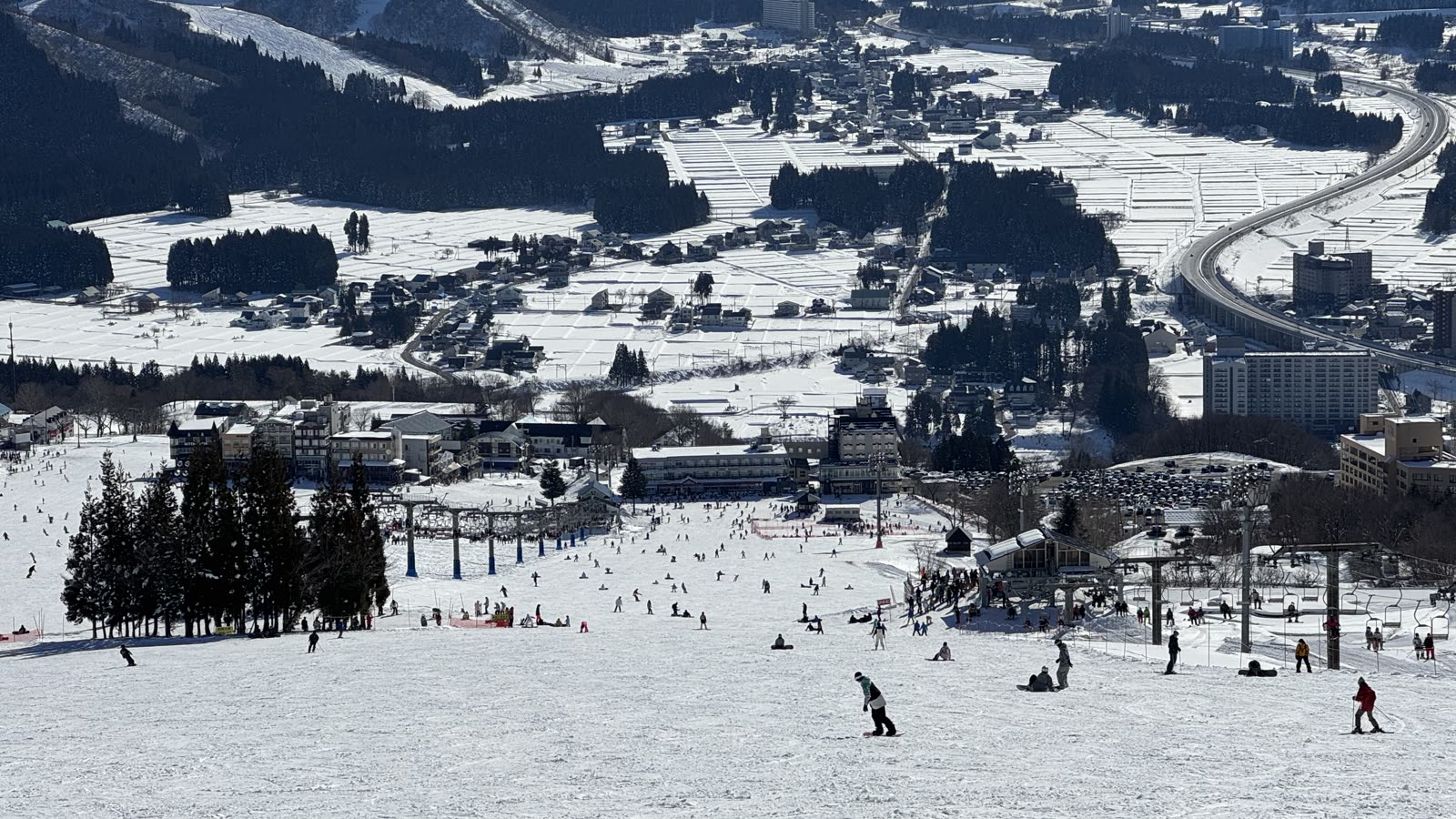 從岩原滑雪場高處俯瞰整片雪道，遠方是湯澤市街與群山