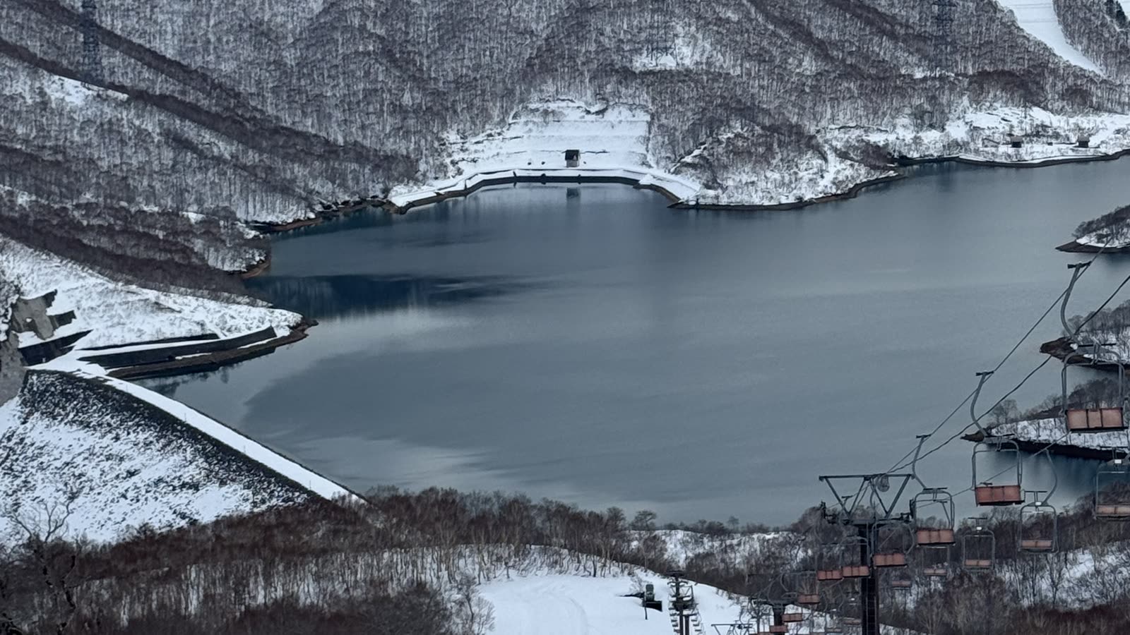 從神樂滑雪場高處俯瞰雪道與湛藍的田代湖，遠方雪山層疊